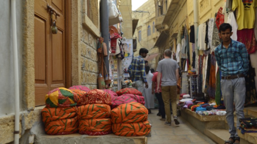 Sacks of produce stacked in a busy bazaar lane