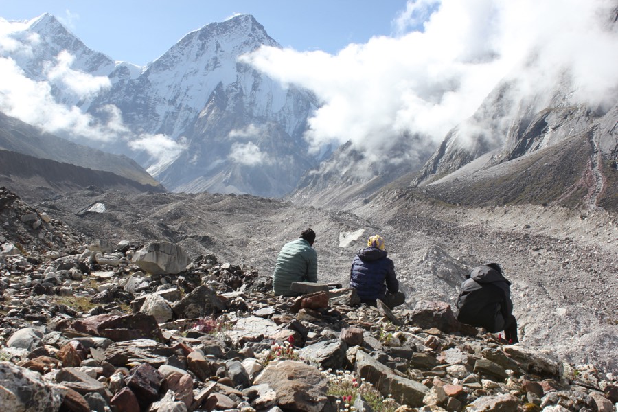 Walkers on a rocky trail beneath snowbound peaks